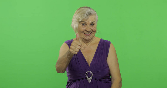 徽标ps素材一位老妇人竖起大拇指微笑一件紫色礼服的老俏丽的祖母放置您的徽标或文本色度背景