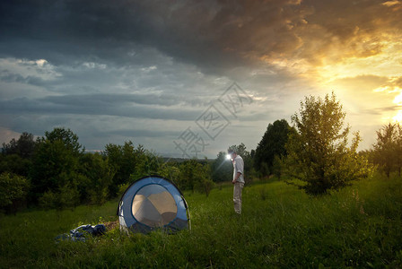 伙计们在草地上搭起了帐篷一个男人教男孩露营背景中的和山脉太阳进来了图片