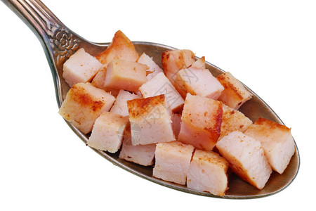在旧金汤匙里有一小片食物烧烤炒火腿猪肉的夸尔切片在白色工作图片