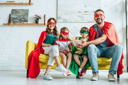 家庭快乐穿着超级英雄的服装吃爆米花图片