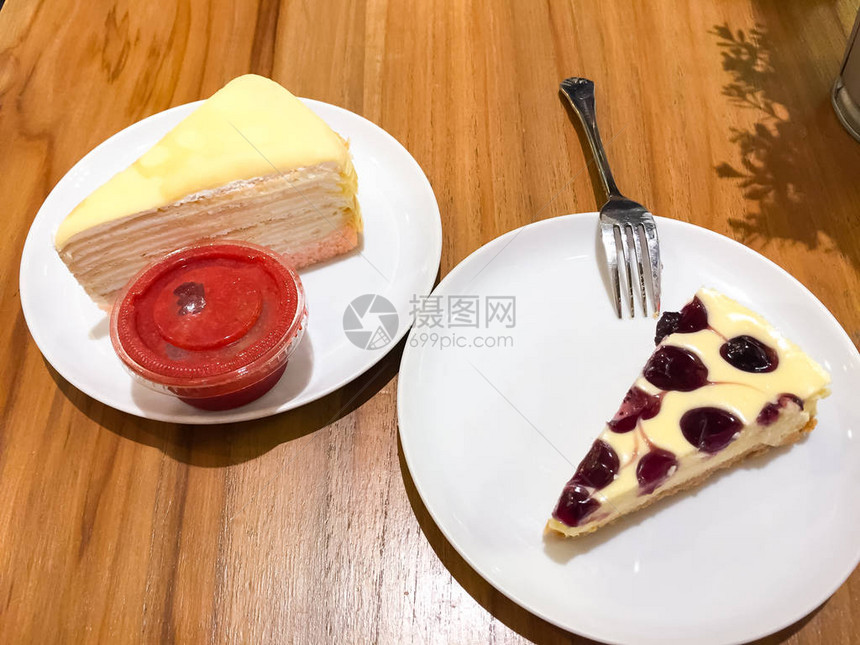 蓝莓芝士蛋糕和果冻蛋糕加草莓酱都放在白盘上图片