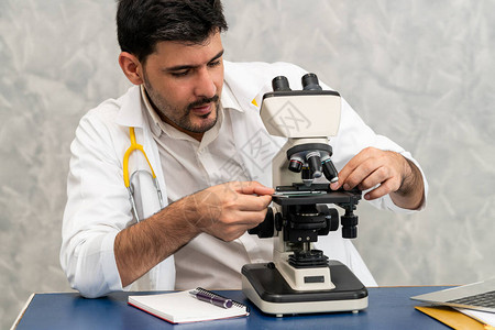 年轻的男医生在医院实验室使用显微镜工作医疗和医药图片