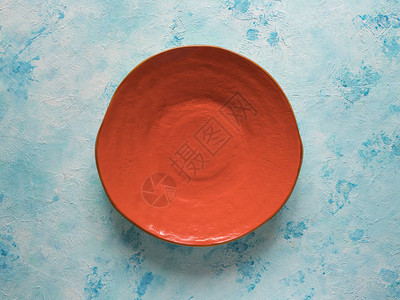 蓝色背景上手工制作的橙色陶瓷板图片