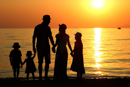 夏天海边日落时的家庭剪影图片