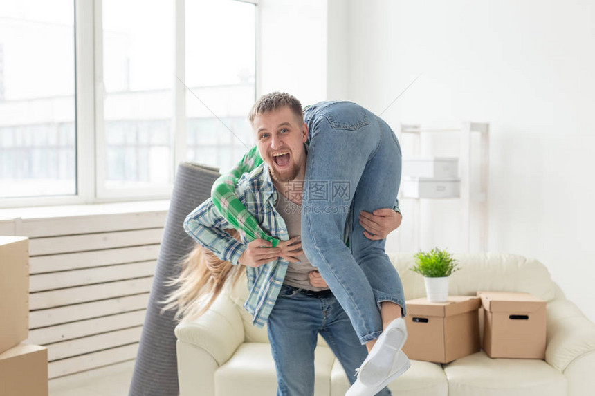 年轻的疯狂夫妇穿着牛仔裤在搬家期间在他们的新公寓里玩得开心乔迁新居理图片