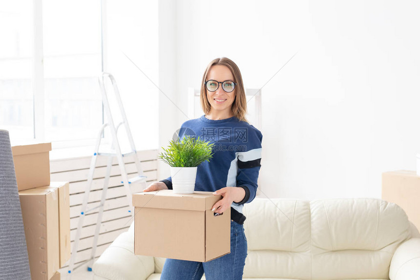 年轻女子搬到新公寓时拿着一个盒子和一盆植物乔迁新居图片