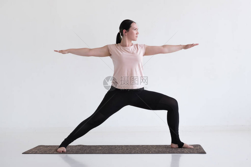 做武士的高加索女人在瑜伽上摆了两个姿势图片