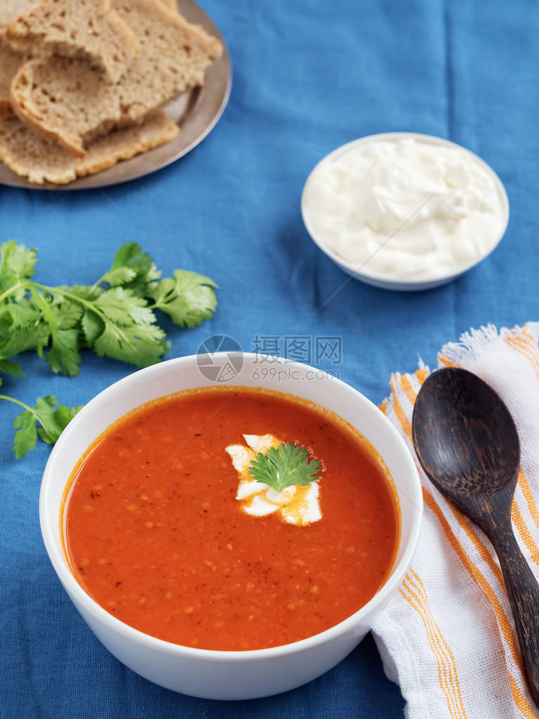 新鲜番茄汤季节夏日菜蓝衬衣桌布白棉餐巾上的勺子酱油面包图片