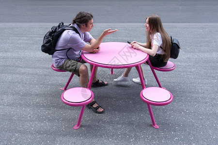 一个男人和一个女孩坐在桌旁聊天女孩拿着电话关图片