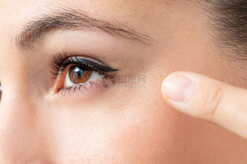 手指向女脸上眼睛周围皱纹的图片