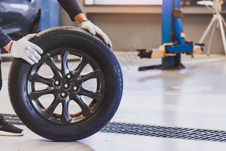 亚洲人机械检查服务维修车持有轮胎或轮胎汽车检查测量数充气橡胶轮胎汽车关闭手推轮到背景图片