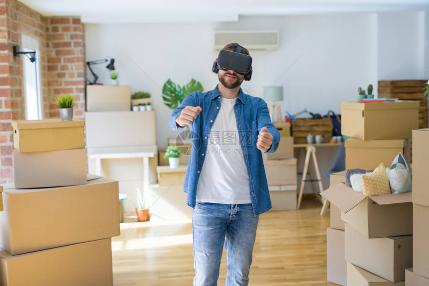 身戴虚拟现实眼镜的年轻人在纸板盒上玩模拟游戏图片