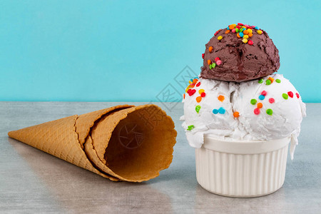 盛满香草和巧克力冰淇淋的勺子洒着巧克力片还有蓝底图片