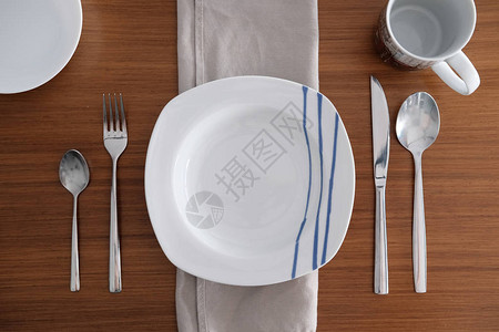 白色瓷器餐具有明亮的金属餐具和木制桌图片
