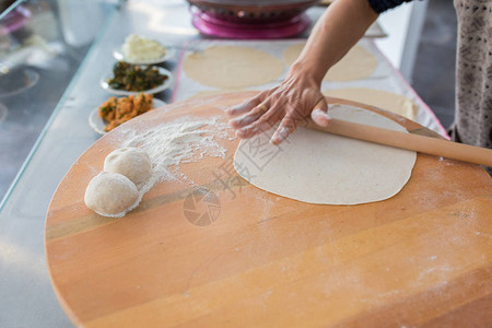 准备或制作面包或面包团的女人手用擀面杖在面团上撒面粉木桌背景上的Borek面包或糕点面团传统的土耳其馅饼皮塔饼或yu背景图片