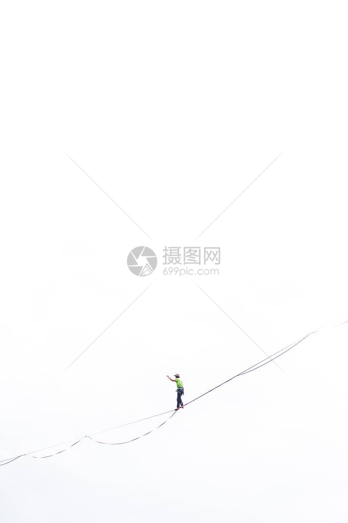 白色背景上的Highliner采取了行动一个人正沿着一条拉长的吊索行走能走钢丝人在深渊中保持平衡向前迈出了图片