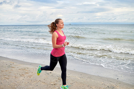 年轻的健身女子赛跑者在海边跑步图片