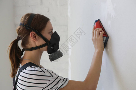 穿着工作防尘面罩和砂墙的年轻女子图片