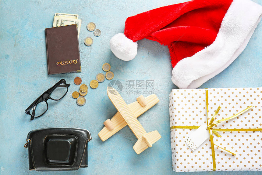 装有礼品盒圣诞老人帽子照相机护照和彩色背景钱财的物品图片