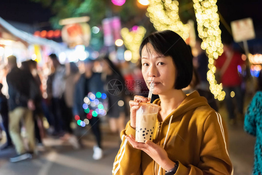 亚裔女在夜市上喝着著名的图片