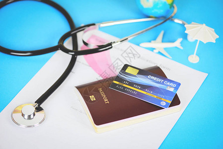 带有护照信用卡和蓝色背景听诊器的旅行保险申请表为健康或全球医疗保健概图片