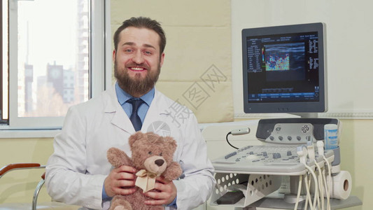 友好的男儿科医生拿着泰迪熊玩具图片