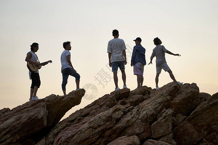 一个摇滚乐队成员站在海边的岩石顶图片