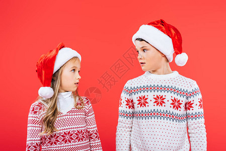 两个穿着圣诞老人帽子的小孩惊讶地看着彼此背景图片