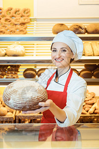 有围裙的女销售员在面包店商展示新鲜面图片