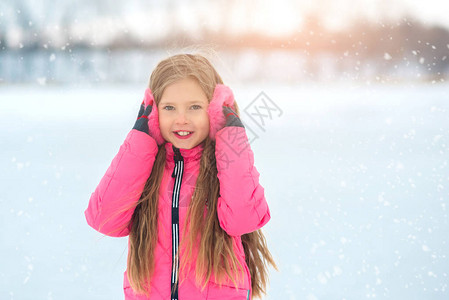 快乐的冬季滑冰女孩在户外溜冰场玩得开心可爱的年轻微笑女孩在冰上张开手的背景图片