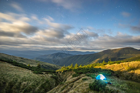 星空和月亮下的山间帐篷里的夜晚之光图片