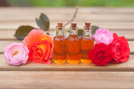 玫瑰油在美丽的玻璃罐子的桌子背景