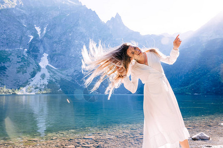 一个长头发和美丽的笑容的女孩在湖边和山上图片