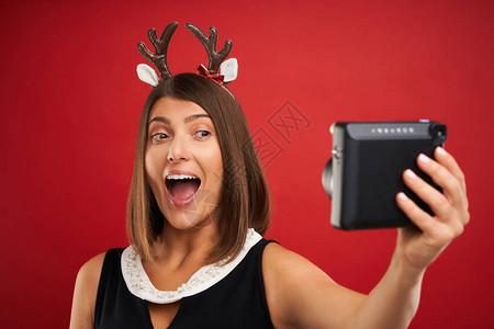 圣诞快乐的女士在红色背景下拍摄即时照片的照片图片