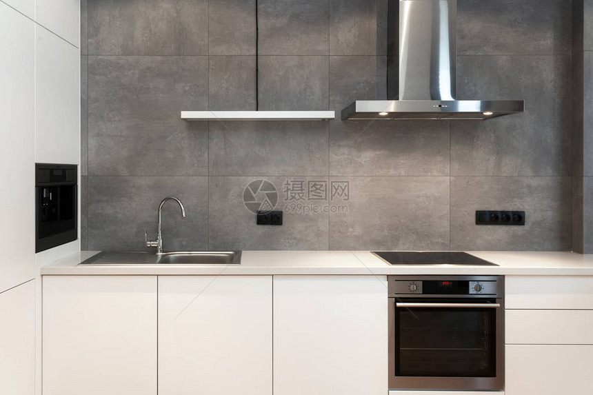 阁楼风格的白色现代厨房的现代室内设计带内置家用电器电炉烤箱台面水槽和灰墙抽油图片