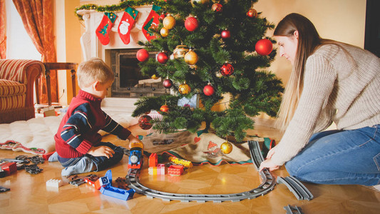 家庭在圣诞节早上在客厅的地板上玩具铁路的图片