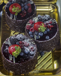 糕点店橱窗上的巧克力蛋糕带浆果覆盆子黑莓蓝莓醋栗和糖粉的圆图片
