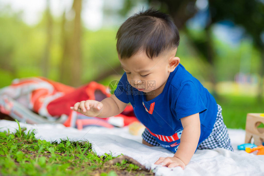 快乐的婴儿宝男孩爬上草地玩耍图片