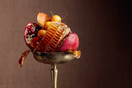 有野苹果和蜂蜜的石榴水果旧黄铜花瓶里的水背景图片
