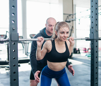 年轻运动女子在健身房一名男教练的帮助下图片