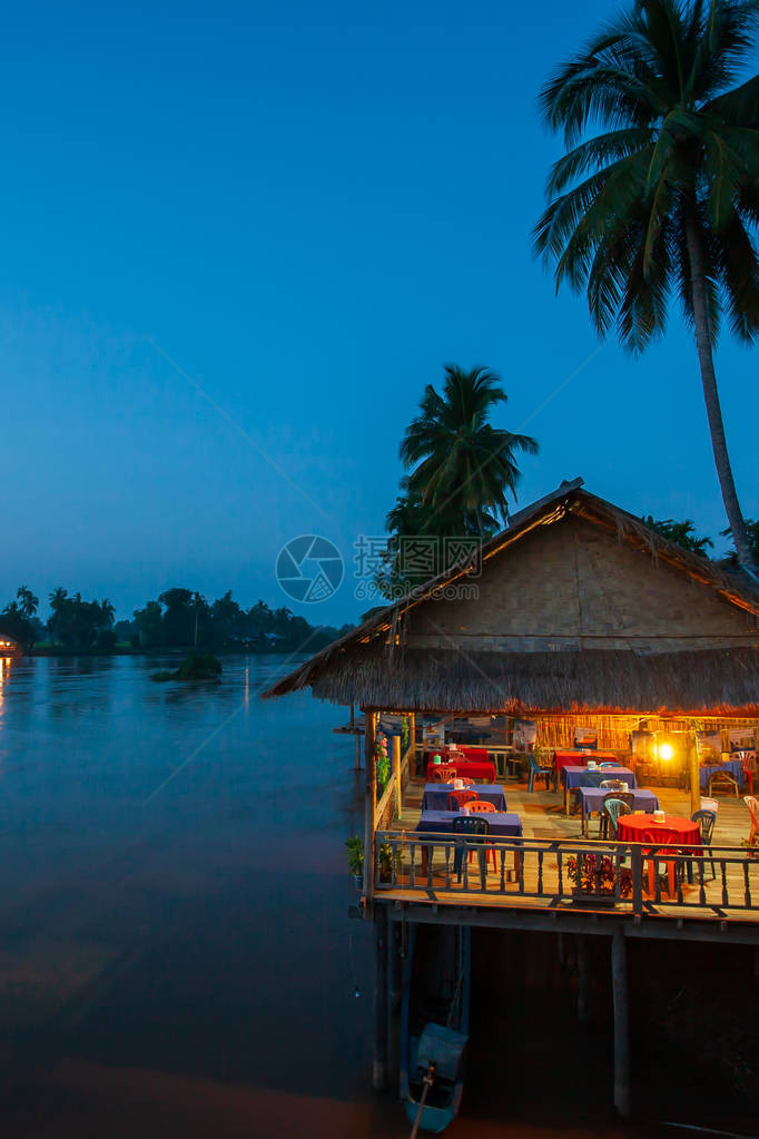 暮色中湄公河附近的河畔餐厅椰子树剪影美丽的灯光餐厅和日落天空背景唐德图片