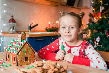 可爱的小女孩用釉料装饰姜饼屋背景图片