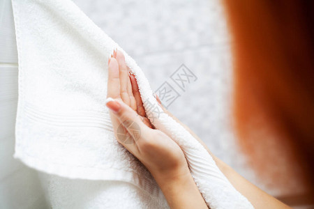 妇女在家里的轻便卫生间洗完澡后用毛巾擦手干燥图片
