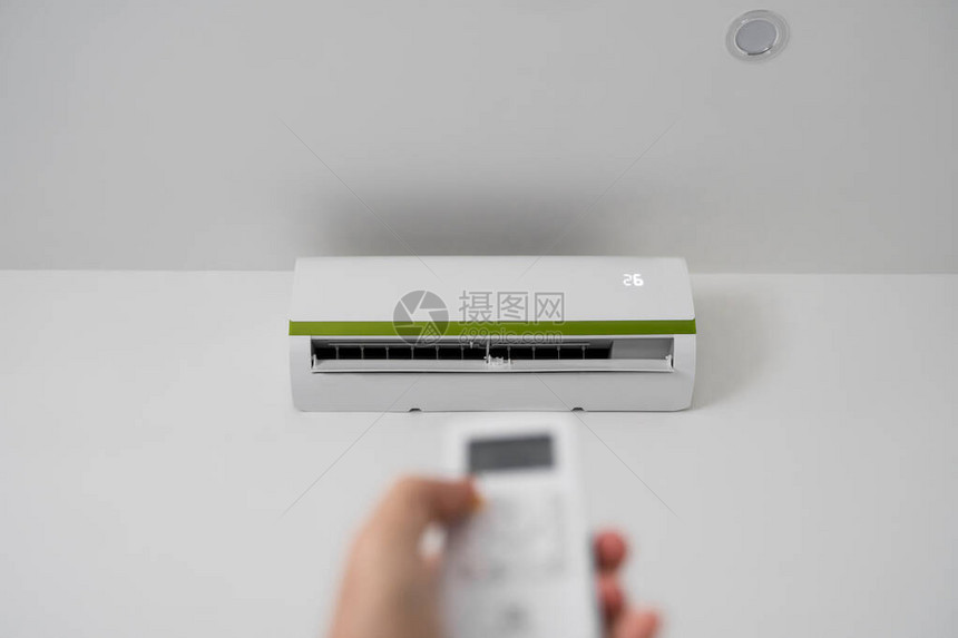 勒芒手使用遥控器手持rc和调节安装在白墙上的空调温度室内舒适温度健图片