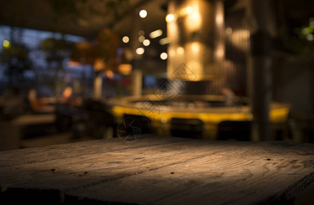 深色下咖啡馆餐厅模糊浅金色散景上的空木桌面背景图片