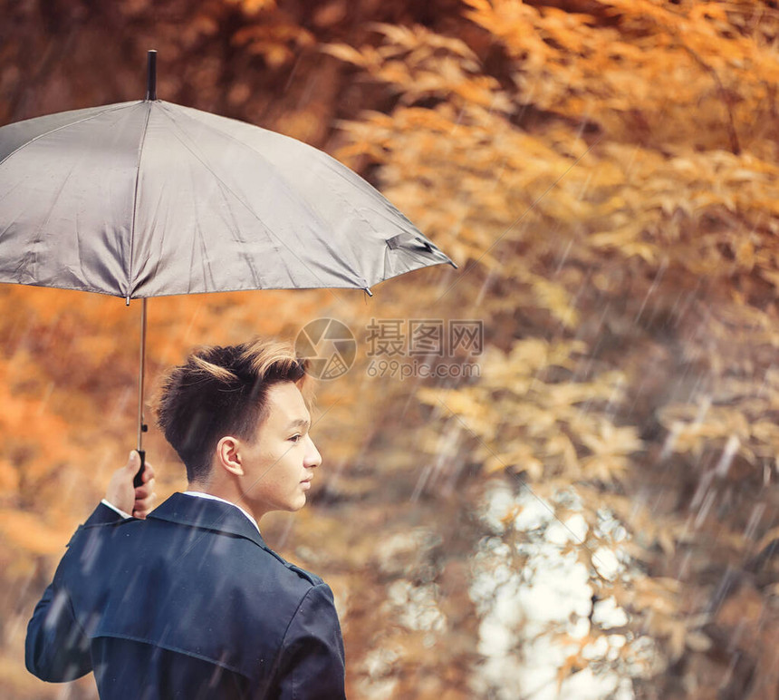 在雨季的秋天公园和一位年轻男图片