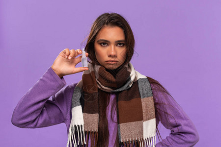 高温来袭穿着毛衣的美籍女围巾紧贴着鼻涕液来治疗普通的寒冷状态与紫色背景隔绝背景