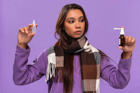 高温来袭穿着毛衣和舒适格子围巾的漂亮非洲裔美国女孩拿着滴鼻剂和喷雾剂来治疗普通感冒背景