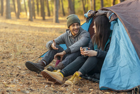 浪漫夫妇在户外露营坐在帐篷里喝茶和聊图片