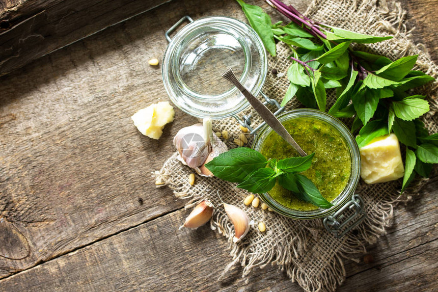 健康的意大利美食绿色香蒜酱与质朴的木桌上的成分平躺的顶视图您的文图片